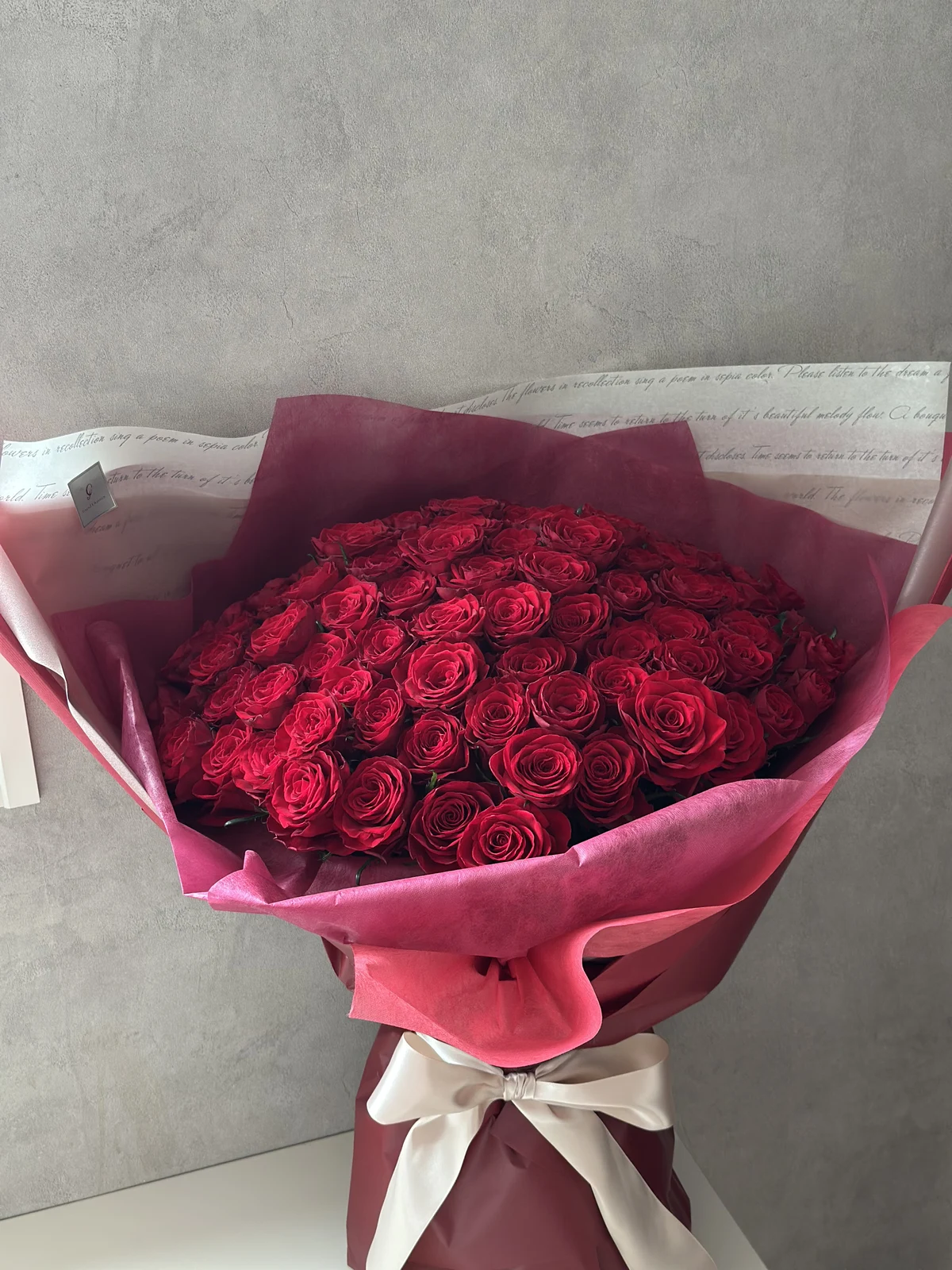 ボルドーのラッピングと白いリボンを合わせた赤薔薇の花束の全体像