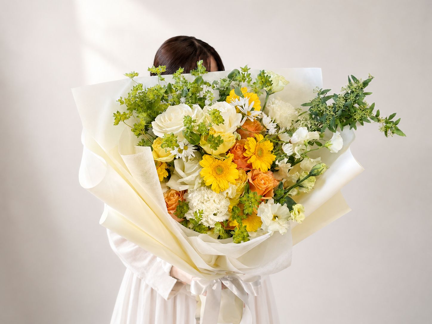 白・黄・オレンジの花を束ねた卒業祝いの花束