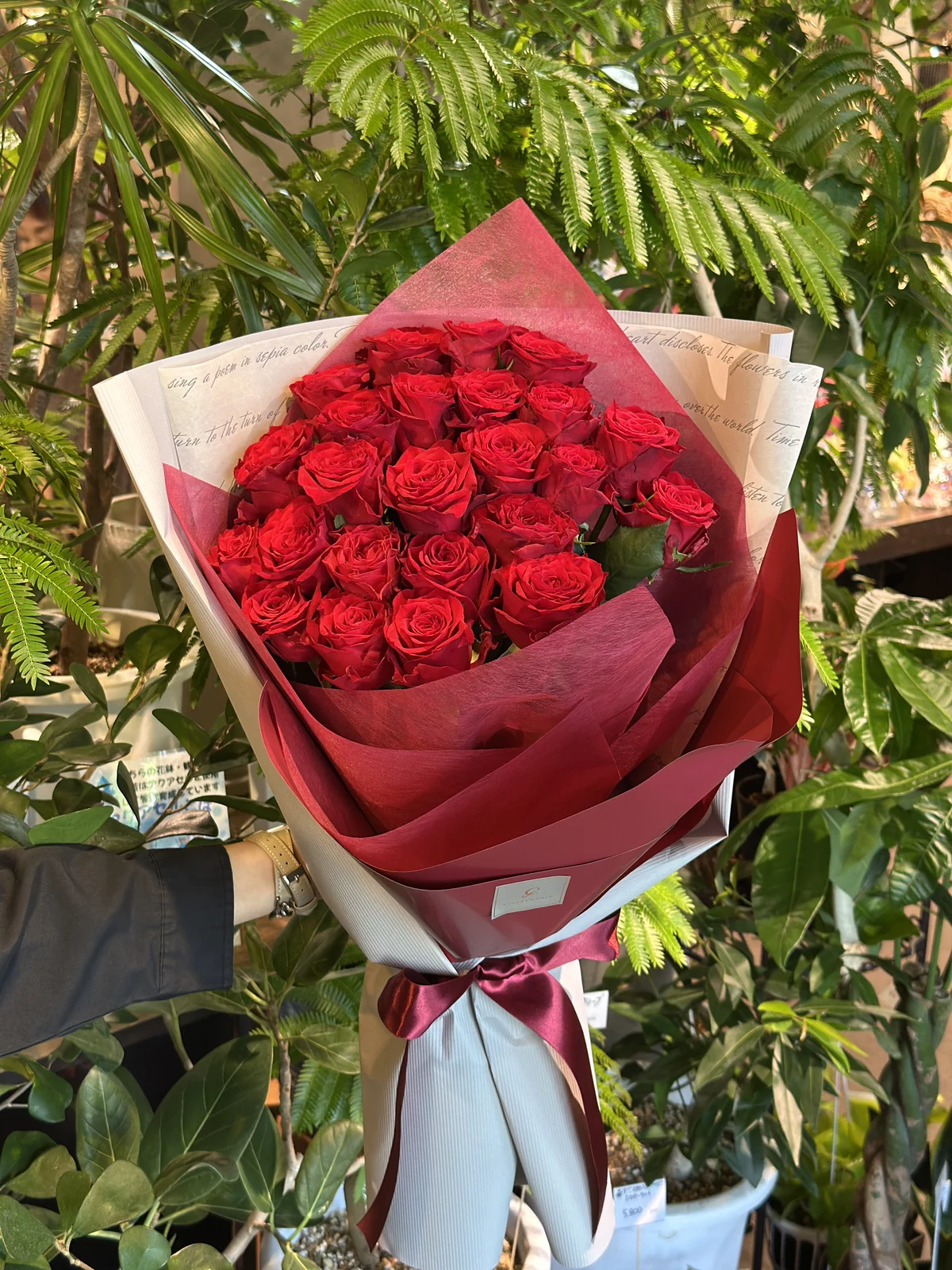 赤薔薇と緑の葉を束ね、赤と白のラッピングで仕上げた花束
