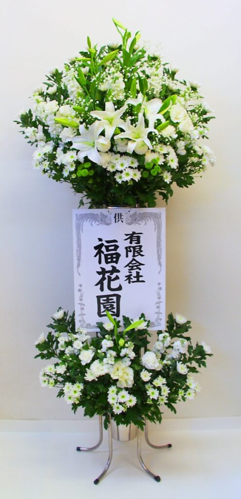 白いユリと菊を生けた葬儀用スタンド花の上段